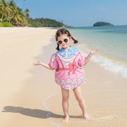 Child wearing a colorful swimsuit by a pool